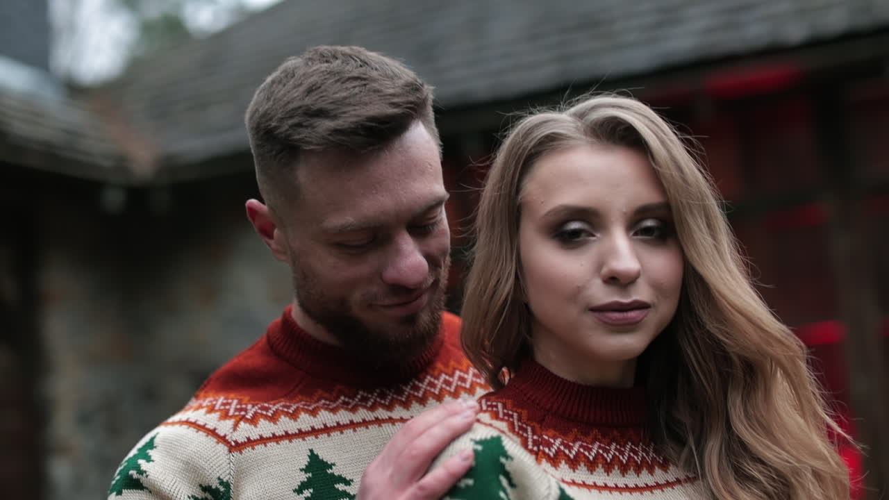 Affectionate couple in the same sweaters standing outdoors. Happy couple having romantic date at the nature background.