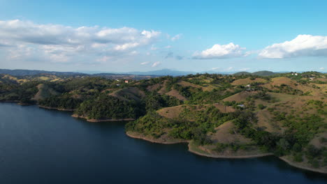 establishing drone shot of lake and green hilly landscape of dominican republic at sunset time