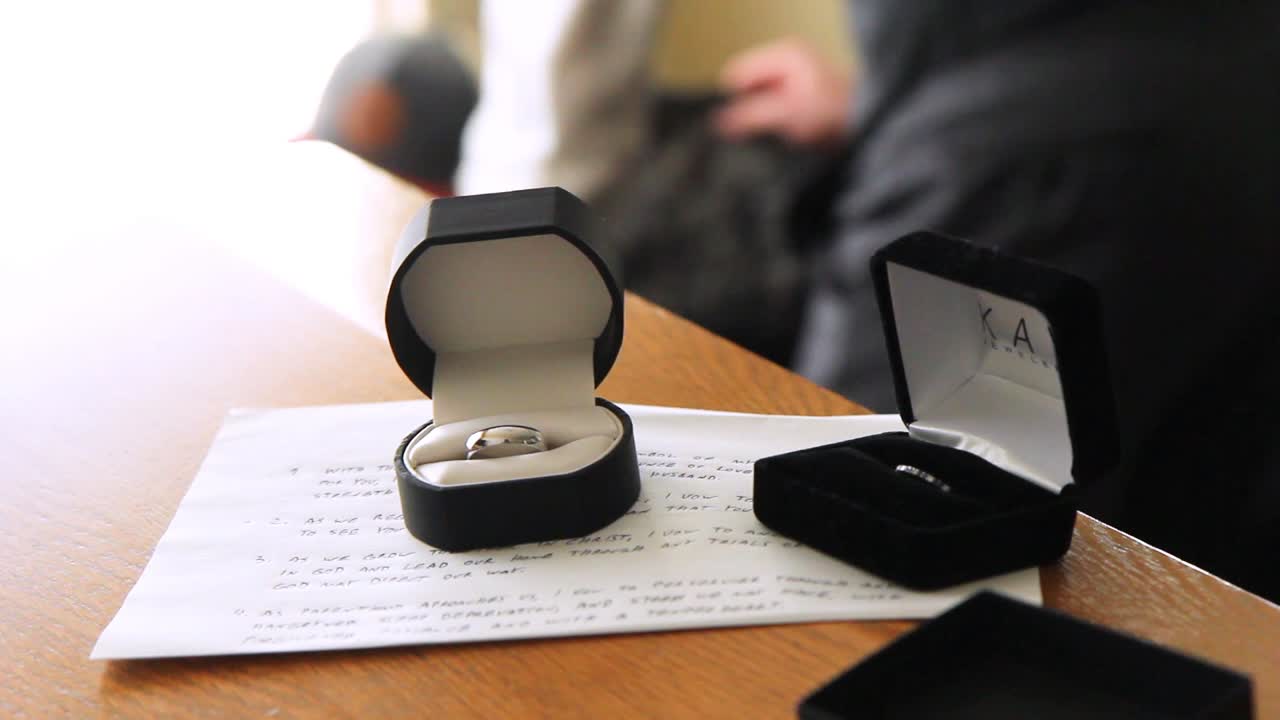 Pan over wedding ring while groom bends over in the background to pick something up