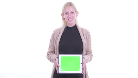 retrato de una hermosa mujer rubia embarazada que muestra una tableta digital con pantalla verde aislada contra un fondo blanco