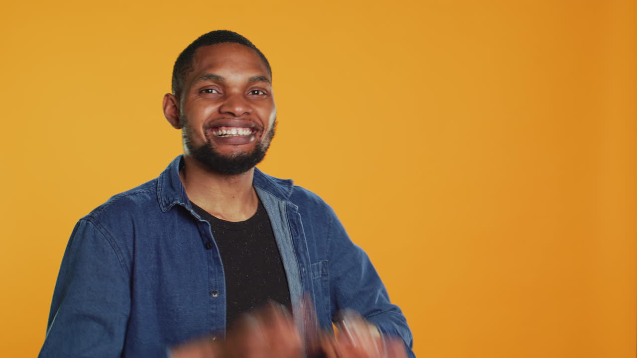Cheerful guy mimics playing drums with two carrots in studio