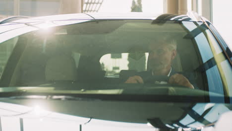 hombre conduciendo un coche en una sala de exposiciones