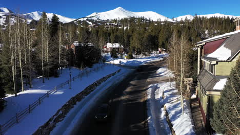 aerial forward view of a mountain road with passing cars and snow capped mountains