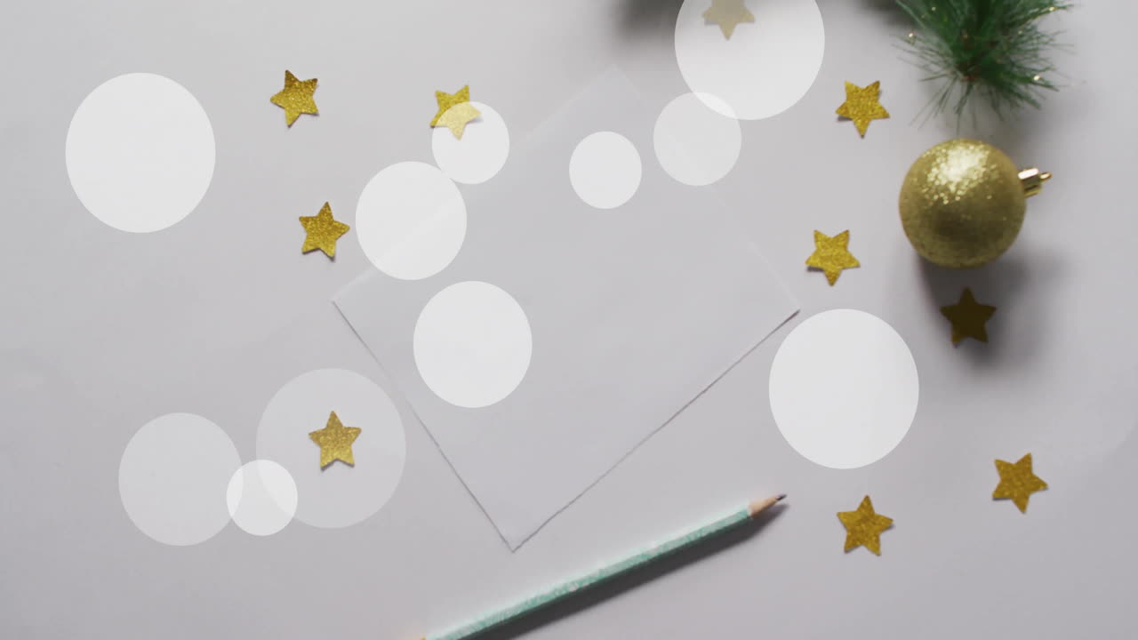Animation of white spots over blank card with christmas decorations on white background