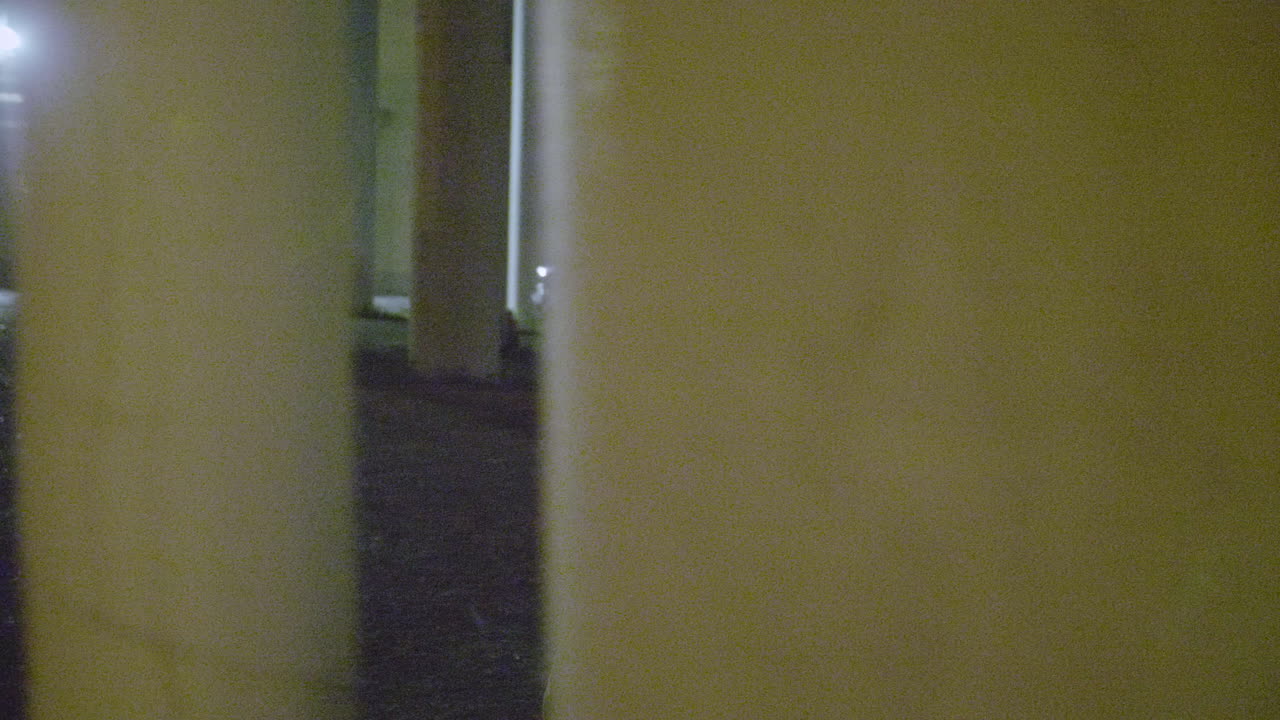 кавказский мужчина идет между колоннами ночью в замедленной съемке