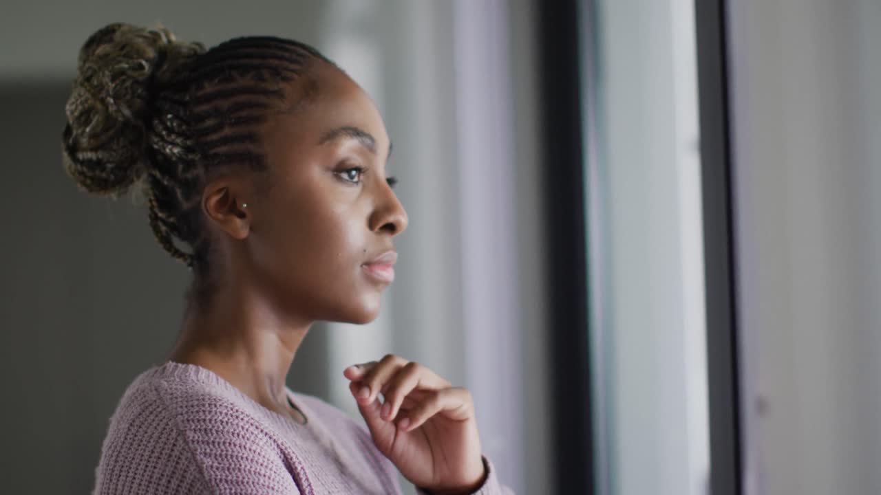 Thoughtful african american woman looking outside window
