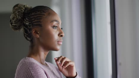 Thoughtful-african-american-woman-looking-outside-window