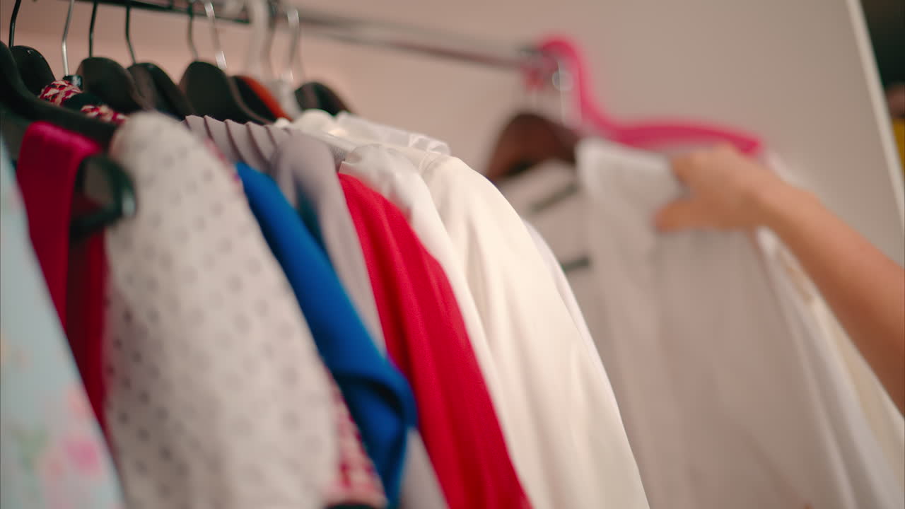 Close-up of Female Hands Plucked Hanger choosing clothes in wardrobe