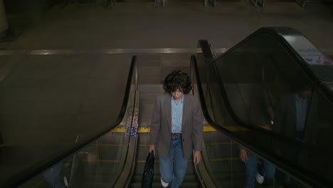 mujer subiendo una escalera mecánica en una estación