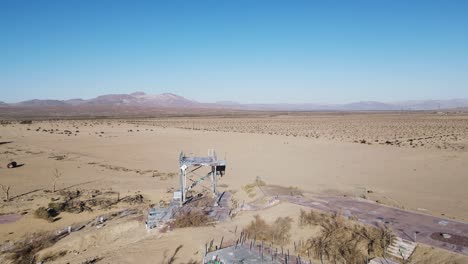 Aerial-footage-going-past-abandoned-structures-toward-the-desert-landscape