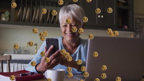 Animación-De-íconos-Emoji-Sobre-Una-Mujer-Birracial-Mayor-Usando-Un-Teléfono-Inteligente