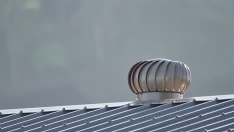 Close-up,-Whirlybird-on-a-metal-roof-spinning-around-in-the-early-morning-sunlight,-Townsville,-Queensland