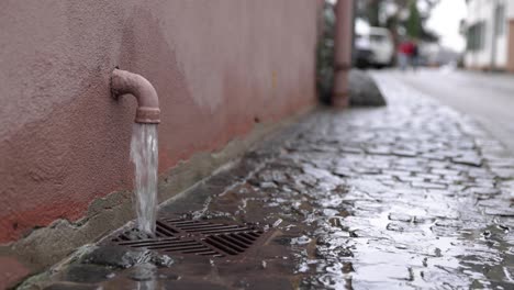 water flowing straight to the drainage canal on the street. wide shot