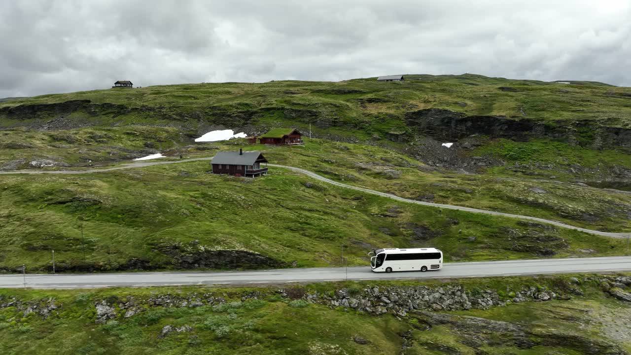 autobús turístico blanco que viaja más allá del paso de montaña de noruega durante el verano - de lado siguiendo el aire