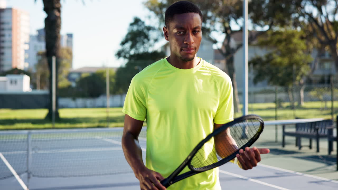 Joven afroamericano sosteniendo raqueta de tenis en una cancha al aire libre