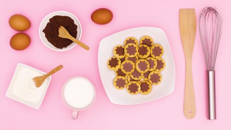 flour, milk, eggs, cacao and cookies in plate move on pink theme. stop motion