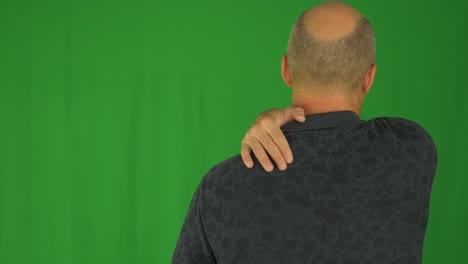 hombre acariciando sus hombros con la mano derecha. vista trasera de la cintura en camisa polo.