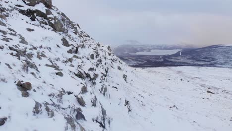 Rocky-frozen-mountain-slope-in-Hemavan-Tarnaby,-in-the-north-of-Sweden---Aerial-fly-beside-shot