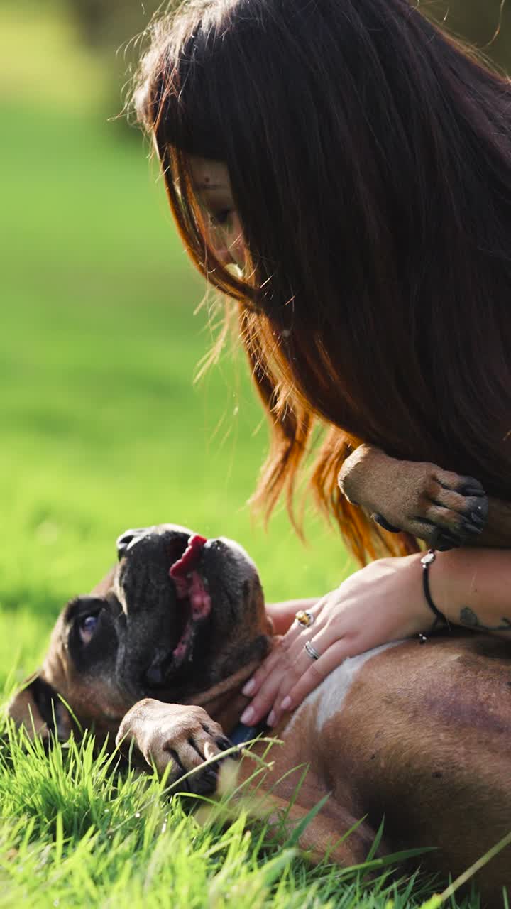 Una mujer jugando con su perro en el césped