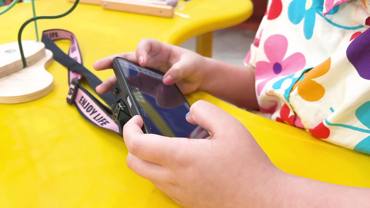 niños usando un teléfono en una mesa colorida