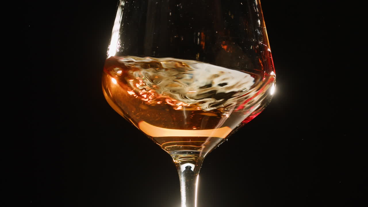 Rose Orange or white wine bottle and glass against a sunset in a peaceful vineyard, pouring of ecological natural wine. Cheers, hands with wine glasses, drinking alcohol.
