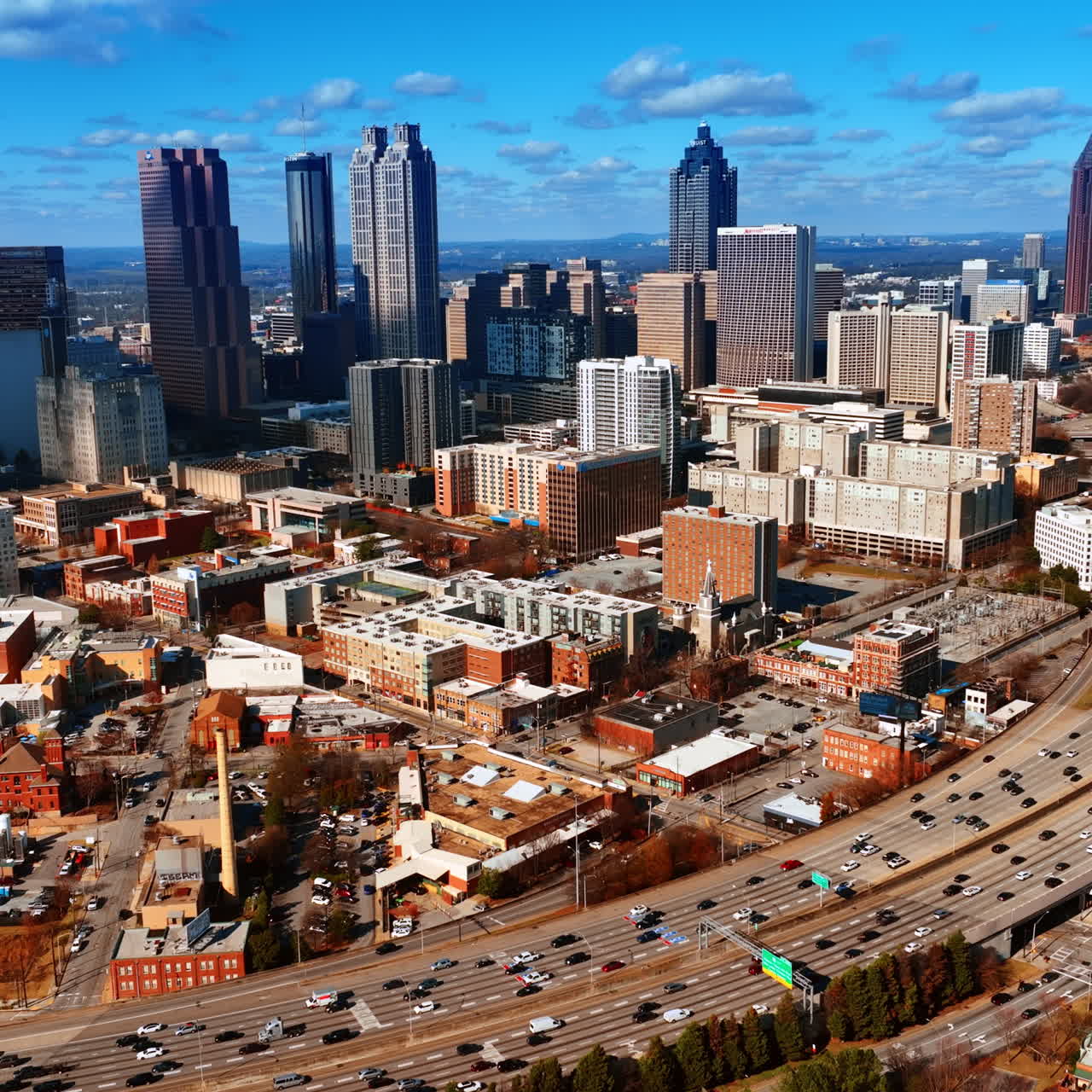 Vast scenery of Atlanta downtown with few skyscrapers in the middle. Lots of cars drive by the wide-lane roads. Top view.