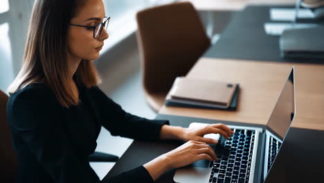 mujer trabajando en una computadora portátil en una oficina moderna