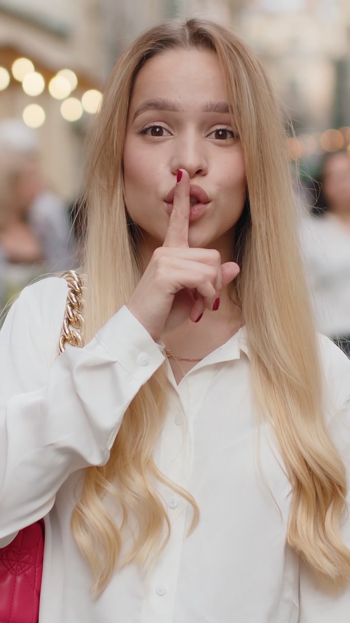 Giovane donna preme il dito alle labbra fa silenzio segno di silenzio non dice pettegolezzi segreto silenzio in città