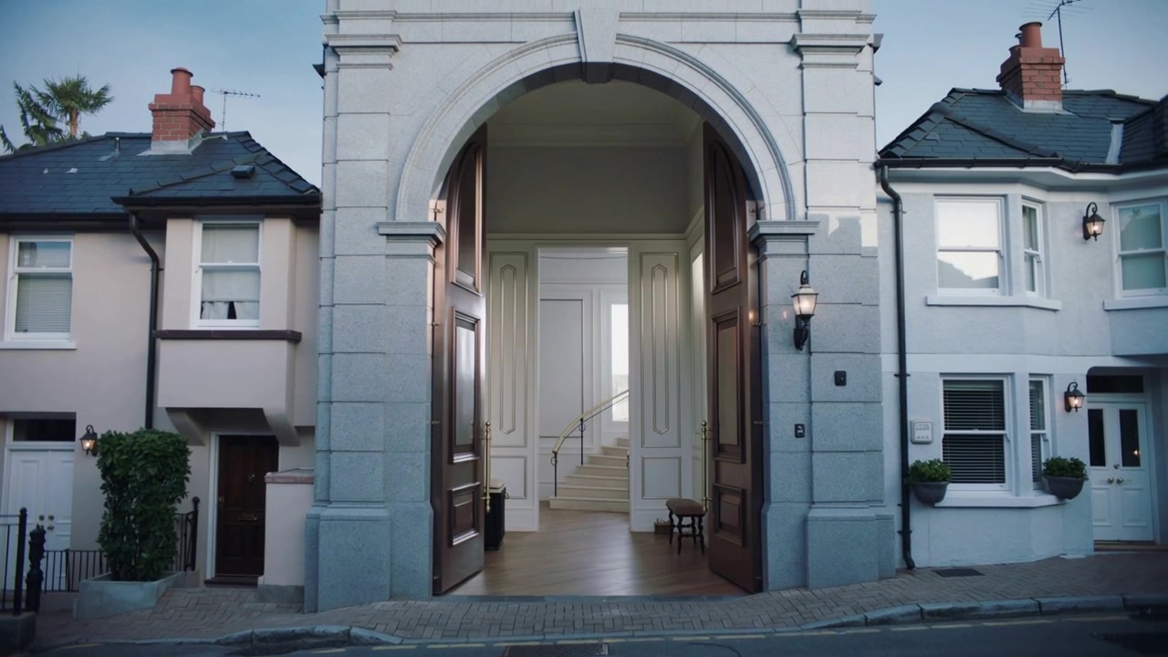 Latch releasing, arched double doors swinging inward on street revealing paneled foyer and stairs