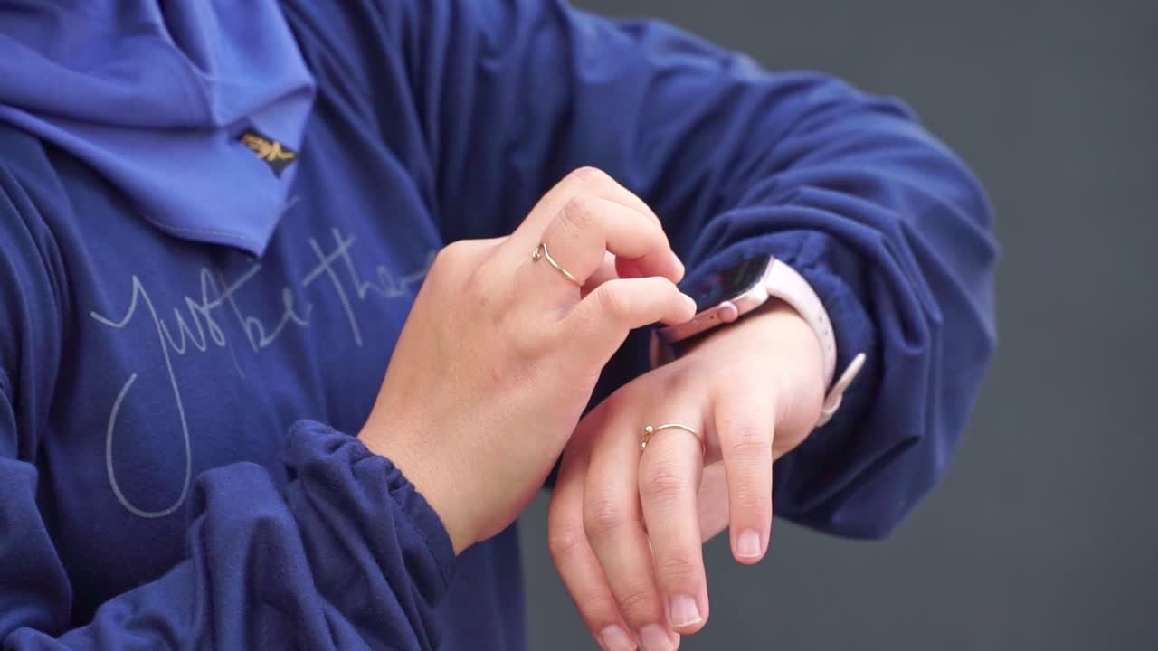 Modern technology concept — Hand of person checking and navigating a smartwatch on their wrist, outdoors in natural light