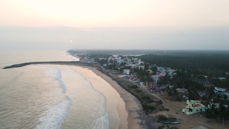 aerial drone shot of kanyakumari with a sweeping view of the ocean and cityscape during a dramatic sunset.