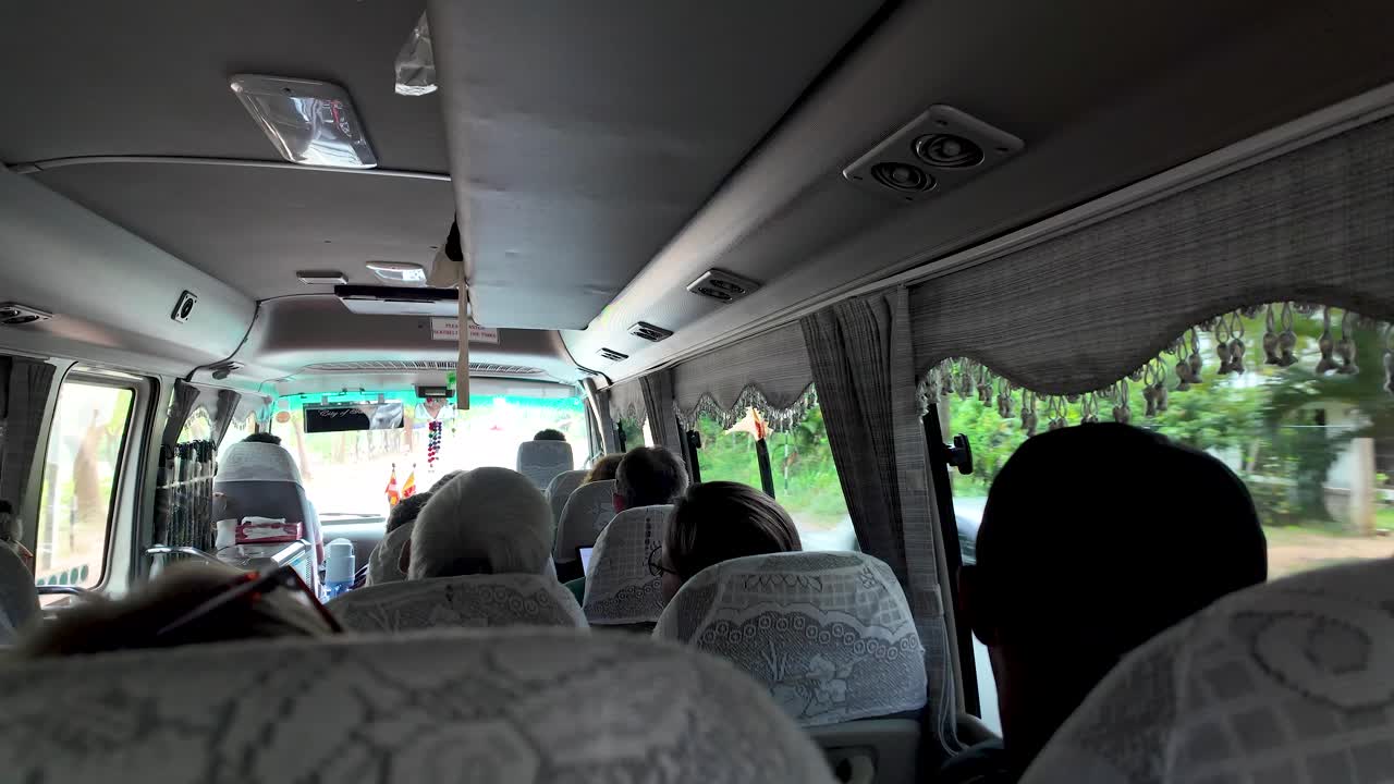 Group of tourists is traveling on a bus and looking out the window at the passing scenery