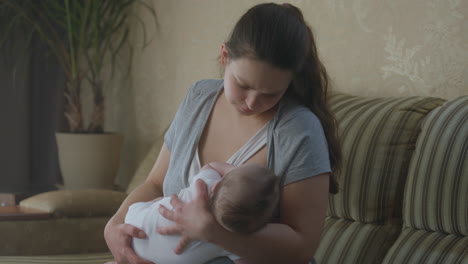 mother breastfeeding baby on sofa