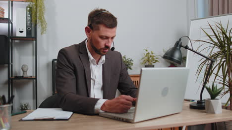 businessman working on laptop wearing headset, call center support service operator office helpline