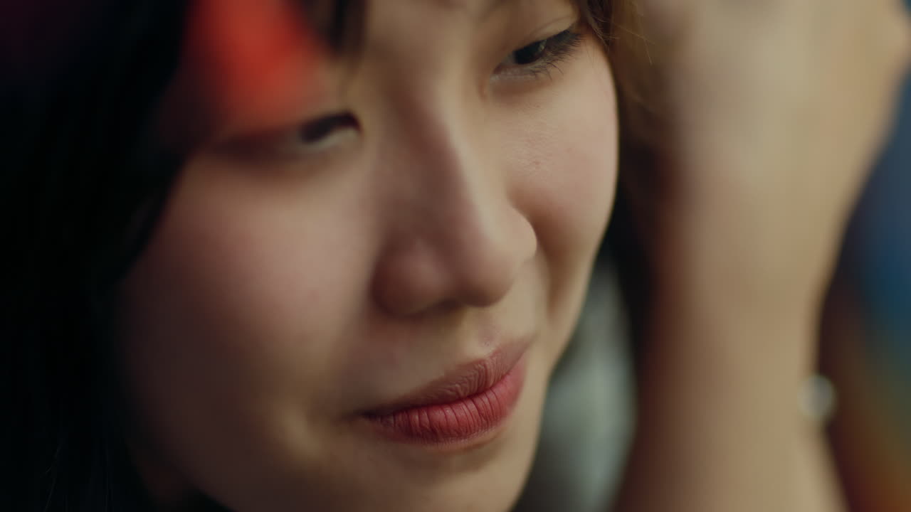 아시안 소녀가 부드럽게 미소 짓고 오른쪽으로 내려다보는 자세한 클로즈업 뷰