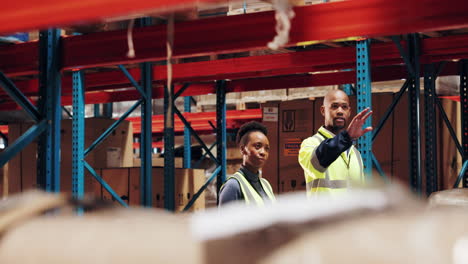 two warehouse workers collaborating on a task in a busy warehouse.