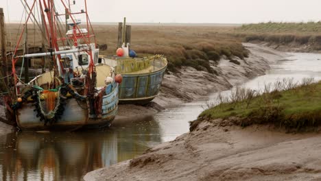 Fishing-boat-moored-on-Steeping-River-at-Gibraltar-Point,-with-the-tide-out-showing-mud-banks