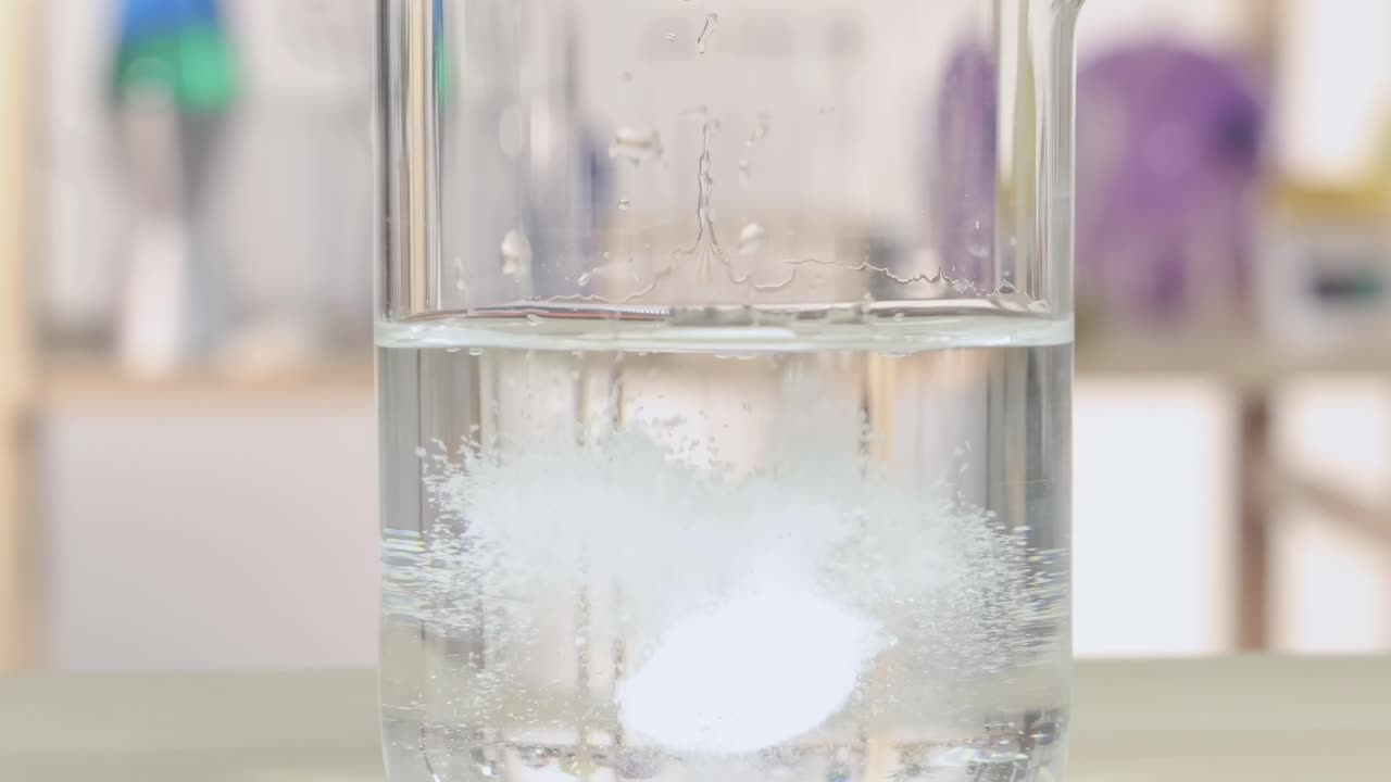 A detailed view of fizzing and gas formation during a chemical reaction in a laboratory beaker.