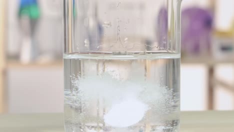 a detailed view of fizzing and gas formation during a chemical reaction in a laboratory beaker.