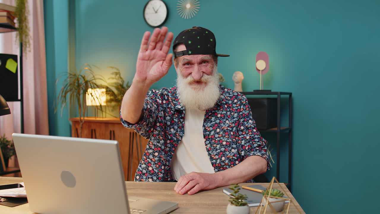 Happy senior man waves hand hi hello gesture greeting welcomes someone online webinar conversation