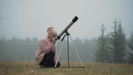 dziecko zainteresowane astronomią i nauką. mała dziewczynka patrząca przez teleskop w naturę.