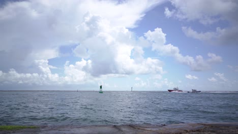 A-fishing-boat-flies-into-the-channel-between-jetties-as-waves-lap-up-onto-the-granite-rocks-in-Port-Aransas,-Texas-on-the-Gulf-of-Mexico