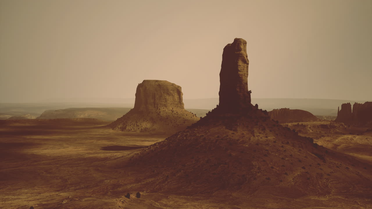 Monumental rock formation in a vast desert landscape during sunset hours
