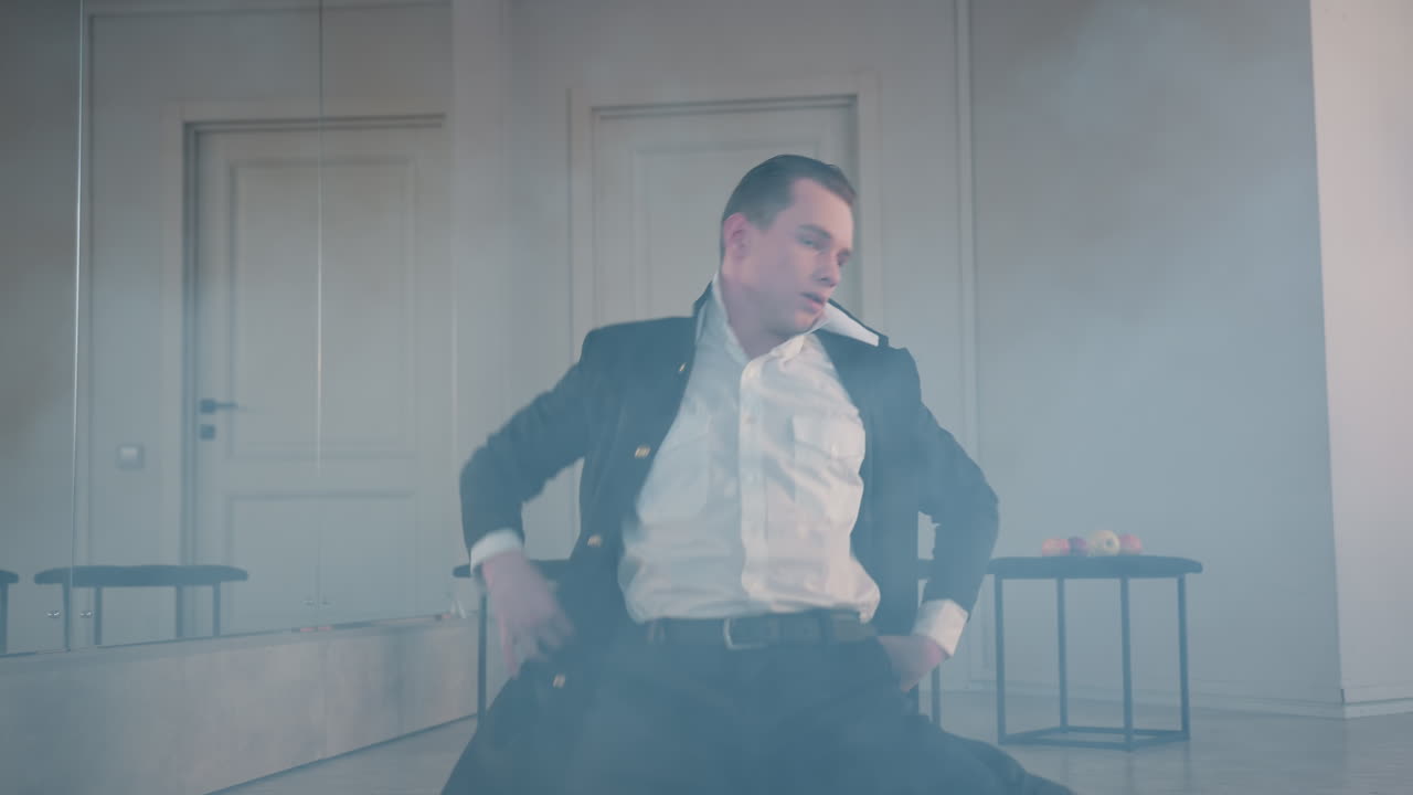 melodramatic dancer lies on ground enveloped in swirling smoke across studio floor, capturing intense emotional performance, fluid body movement, moody light, reflective mirror