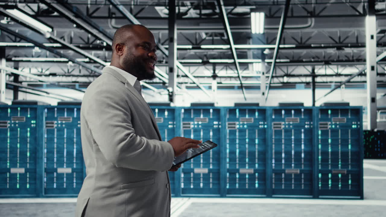 Vertical video Cheerful server room engineer troubleshooting backend operations using tablet