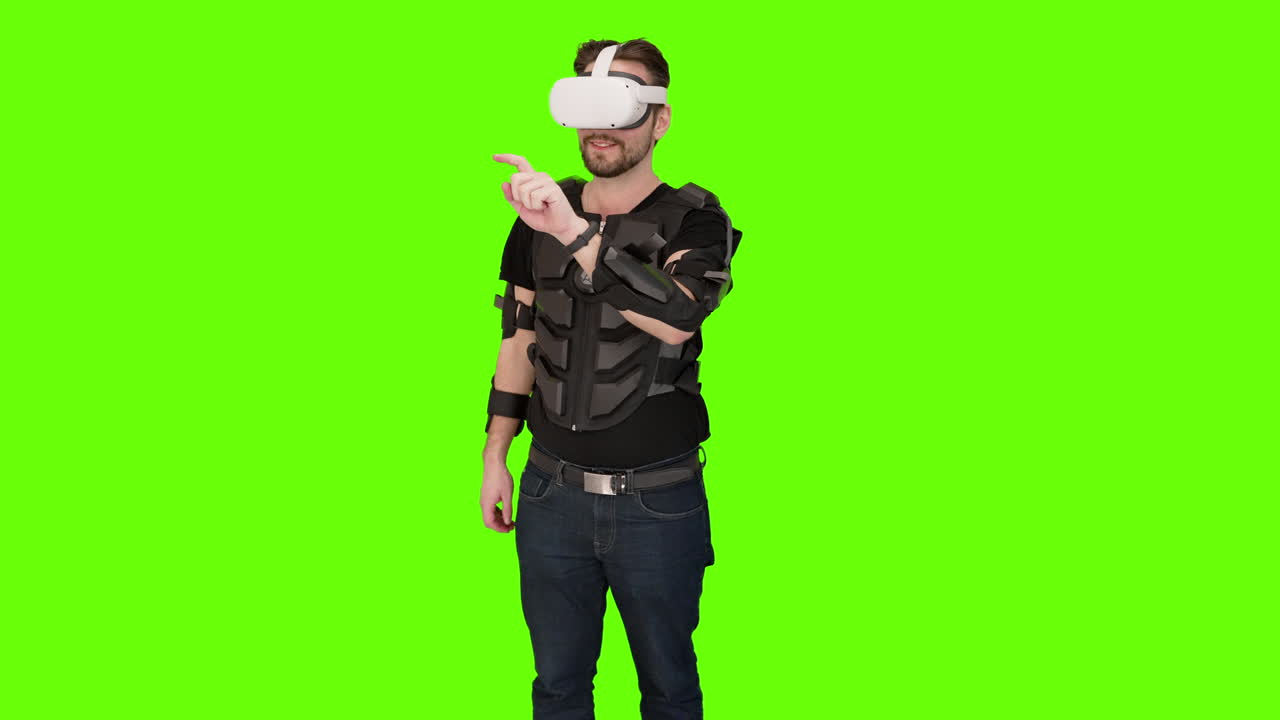 Man in white VR oculus vr virtual headset pointing and swiping with motion tracker capture vest in front of green screen chroma key playing with mixed augmented reality 3d project advanced technology