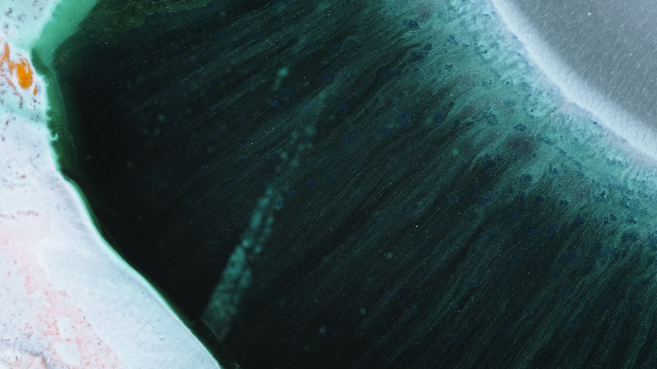 Ink flows organically in macro shot, forming dreamy abstract shapes and textures