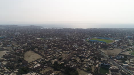 Drone-shot-circling-over-the-skyline-of-Huacho-city,-daytime-in-hazy-Peru