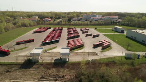 aerial view of parking lot for public transportation buses and trucks. one bus is driving away. industrial background on transportation theme.