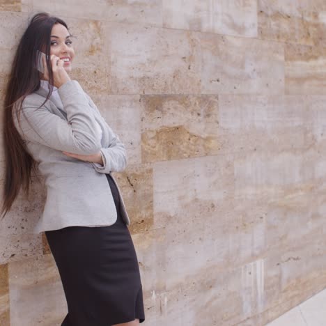 Mujer-Feliz-Hablando-Por-Teléfono-Y-Apoyándose-En-La-Pared